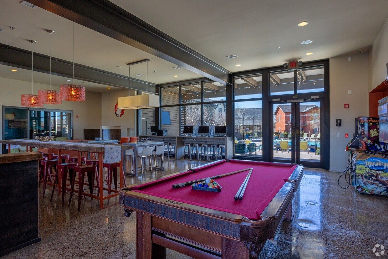 Clubhouse lounge with a pool table, bar seating, and windows to the pool