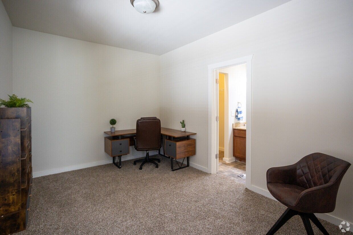 Bedroom staged as a home office with a desk and lounge chair